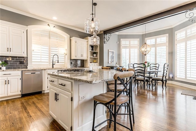 kitchen featuring white cabinetry, stainless steel dishwasher, a breakfast bar area, and a center island