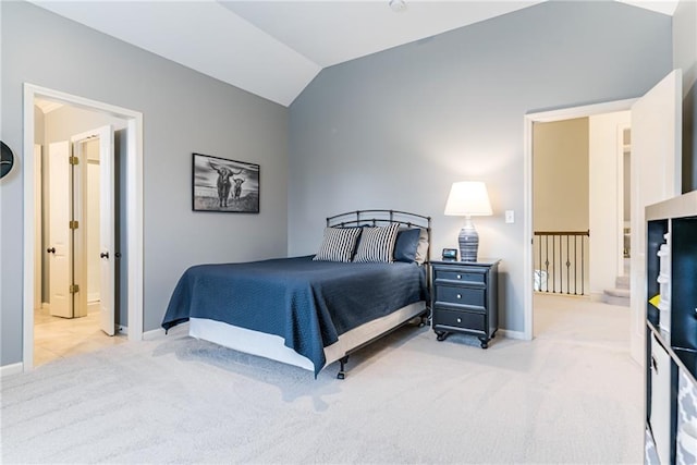 bedroom with lofted ceiling, connected bathroom, and light colored carpet