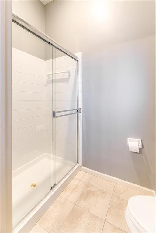 bathroom featuring a shower with shower door and toilet