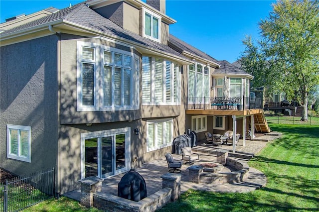 back of property with a patio, a yard, a wooden deck, and a fire pit