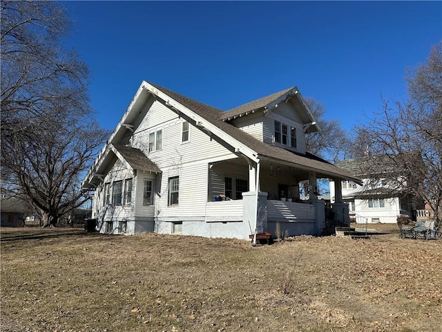 view of side of property featuring a yard and covered porch