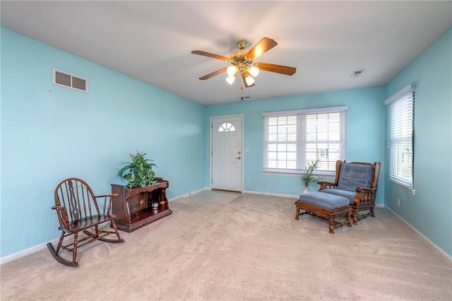 living area featuring a wealth of natural light, visible vents, ceiling fan, and baseboards