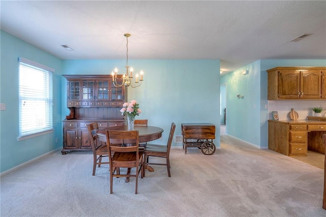 dining space with a chandelier, baseboards, visible vents, and light colored carpet