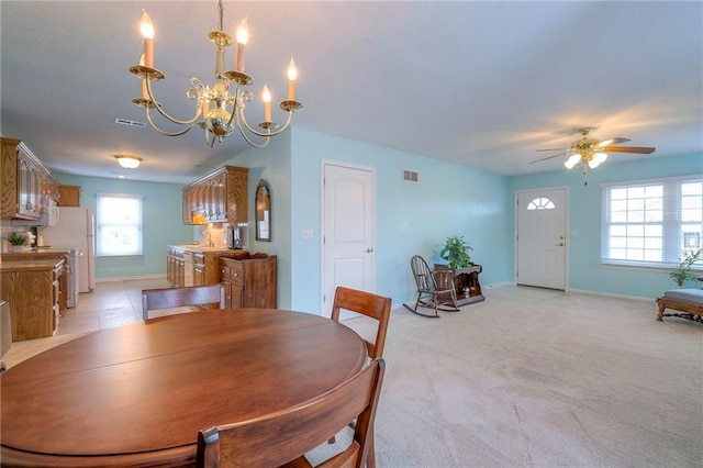 dining space with light colored carpet, visible vents, baseboards, and ceiling fan with notable chandelier