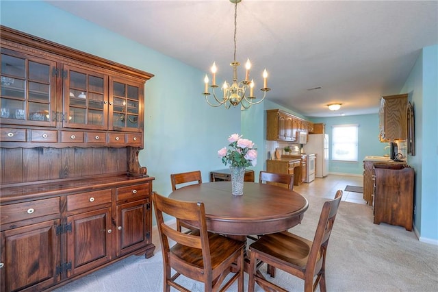 dining area with light colored carpet, a notable chandelier, and baseboards