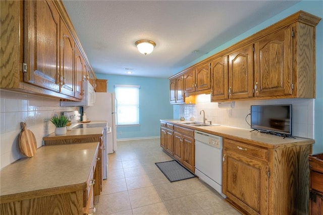 kitchen with electric range, brown cabinetry, white dishwasher, light countertops, and a sink