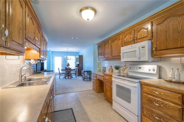 kitchen with a sink, white appliances, brown cabinets, and light countertops