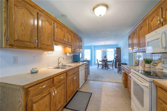 kitchen featuring brown cabinets, decorative light fixtures, light countertops, a sink, and white appliances