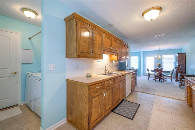 kitchen featuring brown cabinetry, washing machine and dryer, light countertops, and a sink