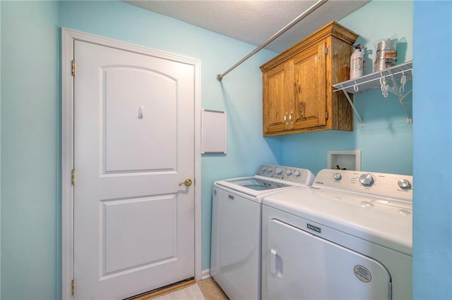 laundry area with cabinet space, a textured ceiling, and separate washer and dryer