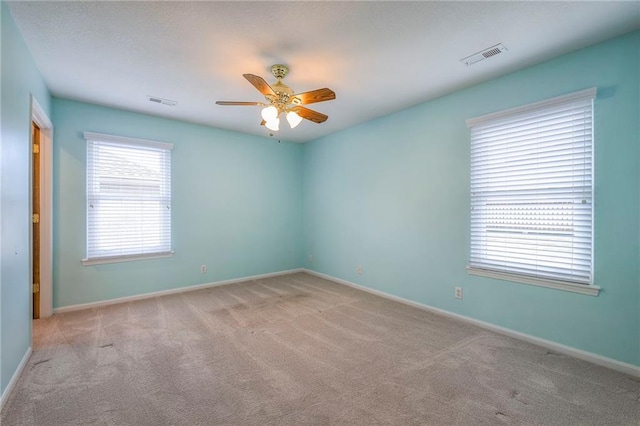 empty room with light carpet, baseboards, visible vents, and a ceiling fan