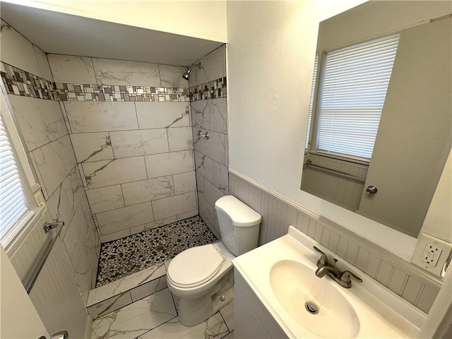 bathroom with vanity, toilet, and tiled shower