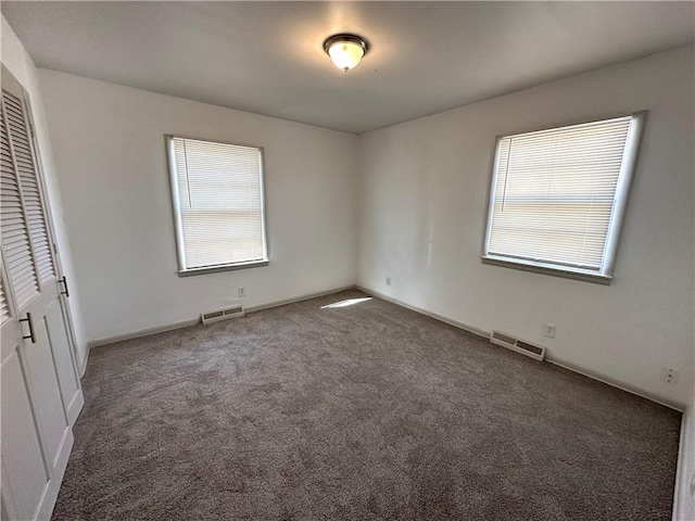 unfurnished bedroom featuring dark carpet and a closet