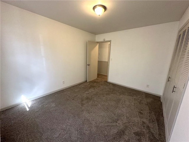 unfurnished bedroom with dark carpet and a closet