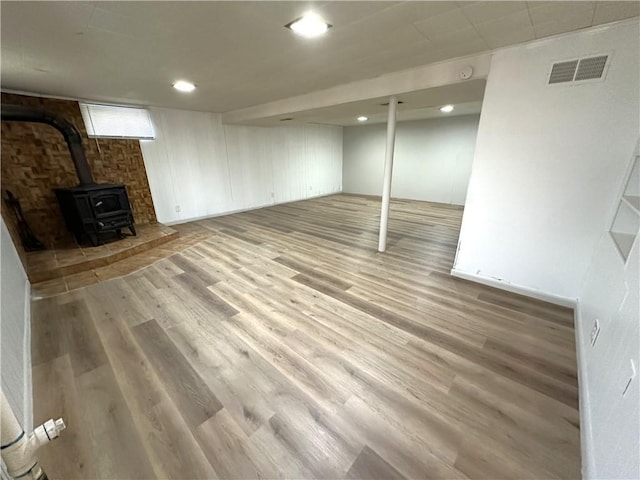 basement featuring hardwood / wood-style flooring and a wood stove