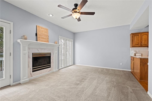 unfurnished living room with light carpet, a premium fireplace, and ceiling fan