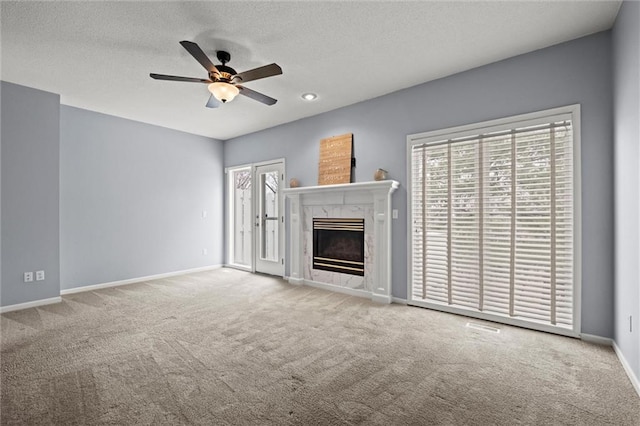 unfurnished living room with ceiling fan, a fireplace, carpet floors, and a textured ceiling