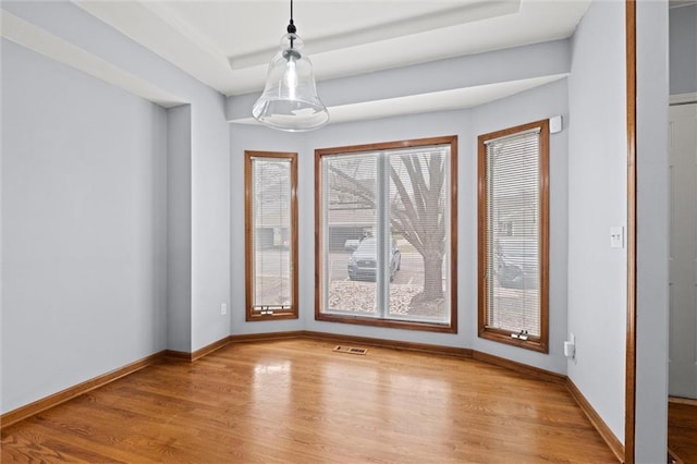 unfurnished room with a raised ceiling and light hardwood / wood-style floors