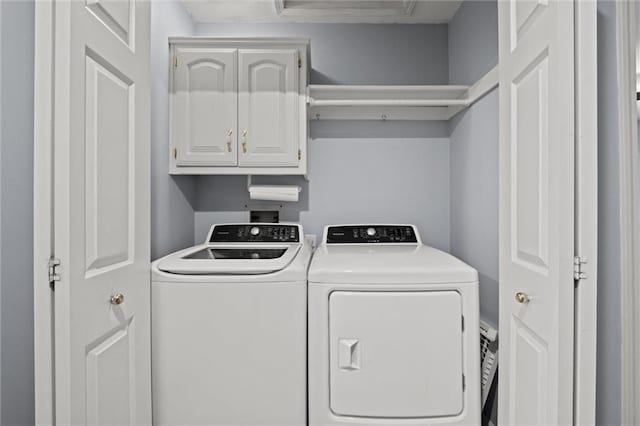 clothes washing area featuring cabinets and washing machine and dryer