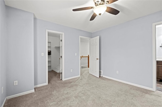 unfurnished bedroom with light carpet, a spacious closet, ensuite bath, and a closet