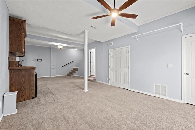 basement with sink, light colored carpet, and ceiling fan