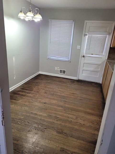 unfurnished dining area featuring a chandelier and dark hardwood / wood-style flooring