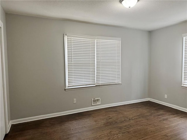 spare room featuring dark wood-type flooring and a textured ceiling