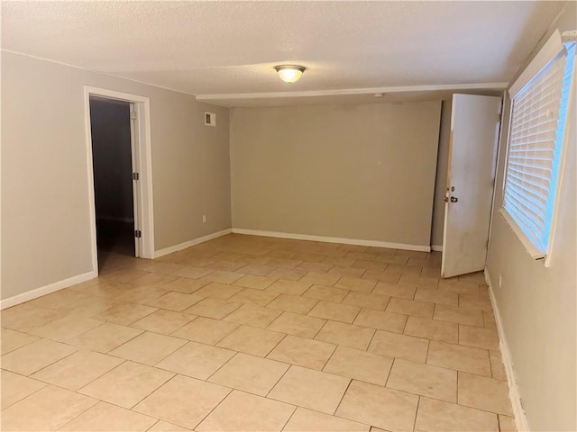 tiled empty room with a textured ceiling