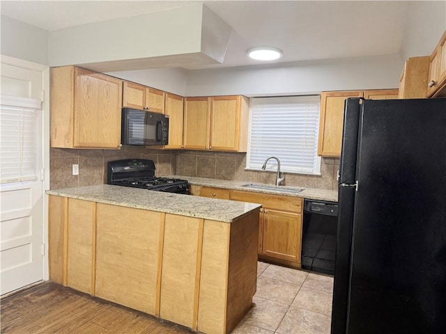 kitchen featuring light stone counters, sink, black appliances, and kitchen peninsula