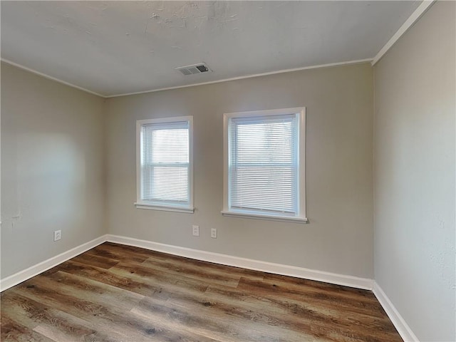 empty room featuring dark wood-type flooring and crown molding