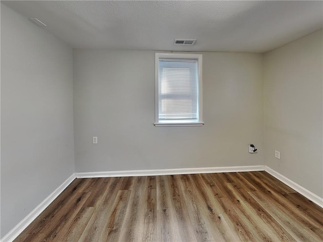 empty room with hardwood / wood-style flooring and a textured ceiling