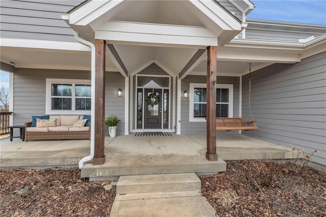 view of exterior entry with covered porch and an outdoor living space