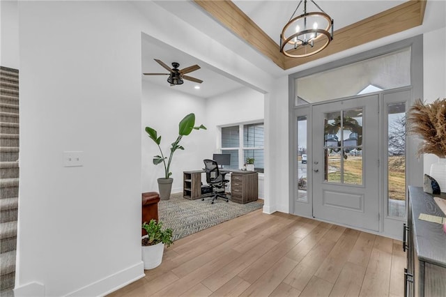 entrance foyer with light wood-type flooring, stairs, baseboards, and ceiling fan with notable chandelier