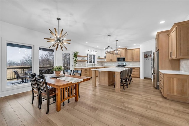 dining area with light wood-style floors, recessed lighting, and a notable chandelier