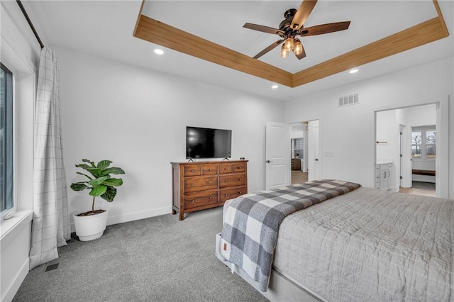 carpeted bedroom with visible vents, a tray ceiling, baseboards, and recessed lighting