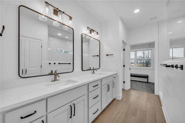 full bath featuring double vanity, visible vents, a sink, and wood finished floors