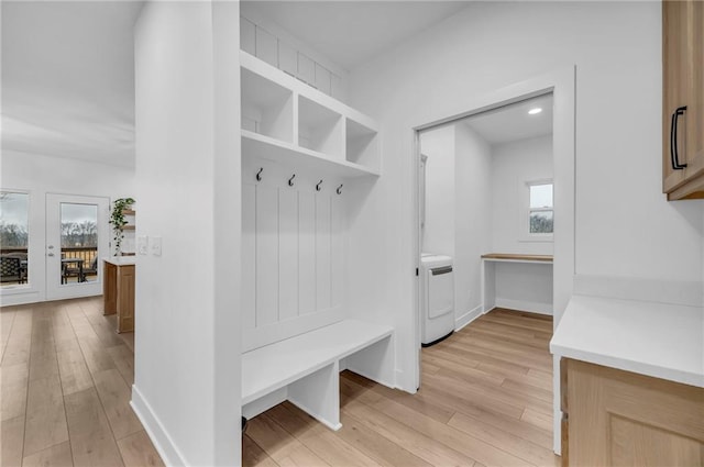 mudroom featuring baseboards, washer / clothes dryer, and light wood-style floors