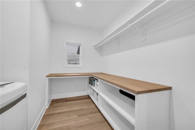 spacious closet featuring built in study area and light wood-style floors