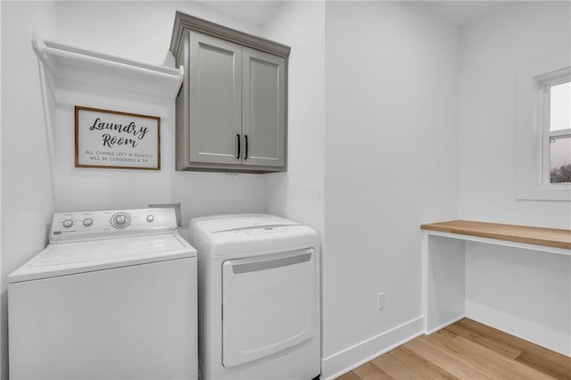 washroom with cabinet space, baseboards, light wood-style floors, and washing machine and clothes dryer