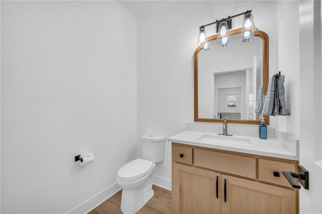 half bath featuring toilet, baseboards, wood finished floors, and vanity