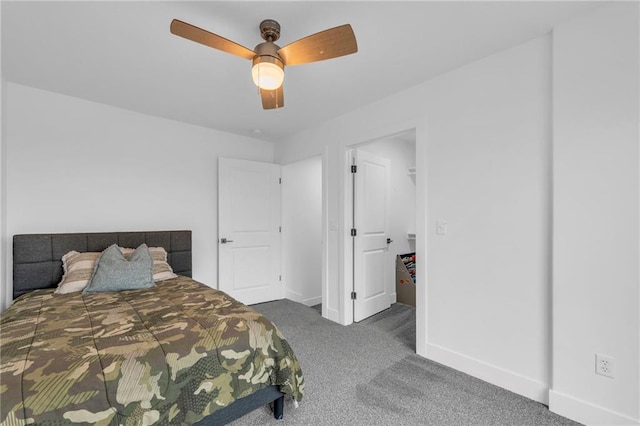 carpeted bedroom with a walk in closet, a ceiling fan, and baseboards