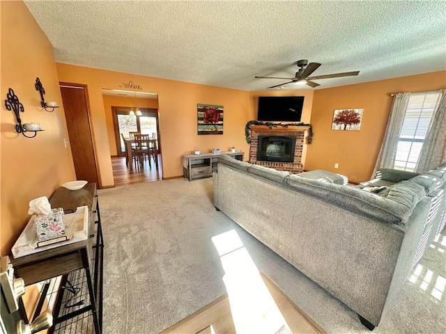 living room featuring ceiling fan, light colored carpet, a healthy amount of sunlight, and a fireplace