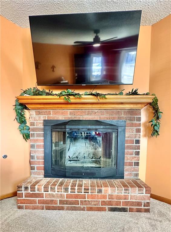 room details featuring a brick fireplace, a textured ceiling, and carpet