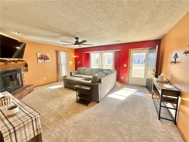 living room featuring ceiling fan, light colored carpet, a brick fireplace, and a textured ceiling