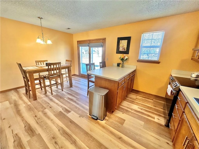 kitchen with range with electric stovetop, pendant lighting, light wood-type flooring, kitchen peninsula, and a textured ceiling