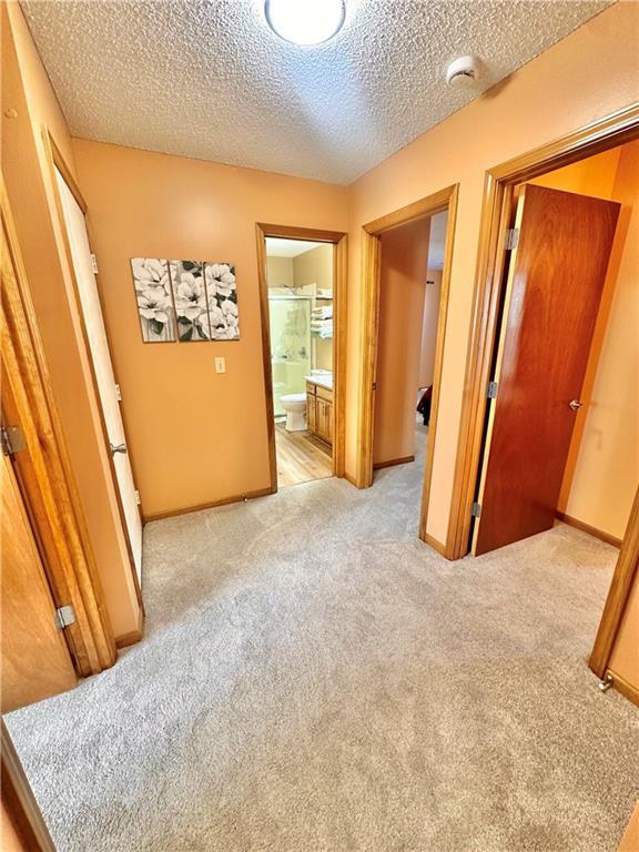 hallway featuring light carpet and a textured ceiling