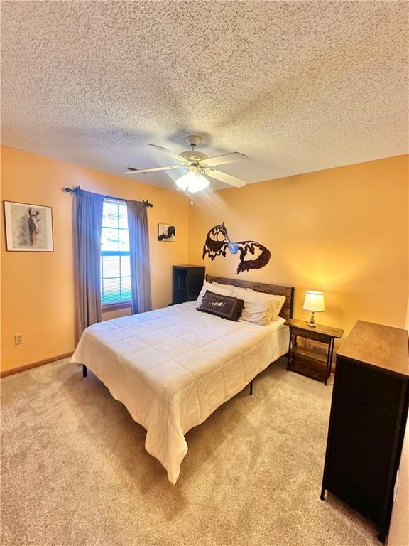 carpeted bedroom featuring a textured ceiling and ceiling fan