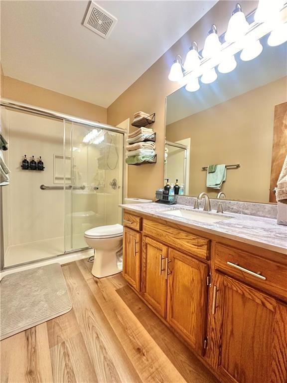 bathroom with vanity, toilet, a shower with shower door, and hardwood / wood-style floors