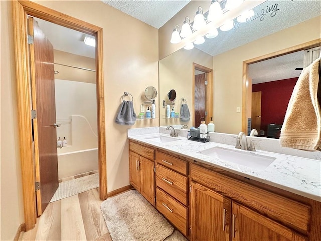 bathroom featuring vanity, shower / bathing tub combination, wood-type flooring, and a textured ceiling