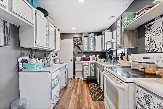 kitchen with light wood-type flooring, white cabinets, sink, and electric range